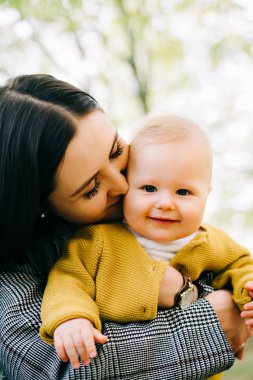 Genç bir anne, küçük mutlu bir oğlanı küçük bir derenin yanında kollarında tutar.