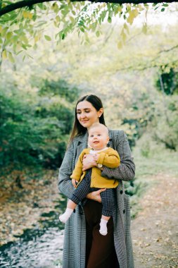 Küçük bir akarsu kenarında kucağında küçük bir oğlu olan genç bir anne.