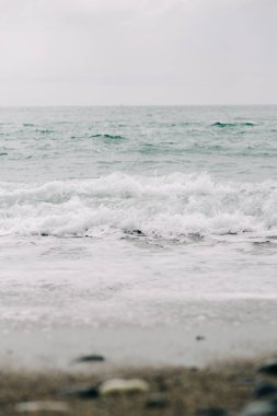 Sahile siyah volkanik kumla bir deniz dalgası geliyor. .