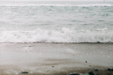 Sahile siyah volkanik kumla bir deniz dalgası geliyor. .