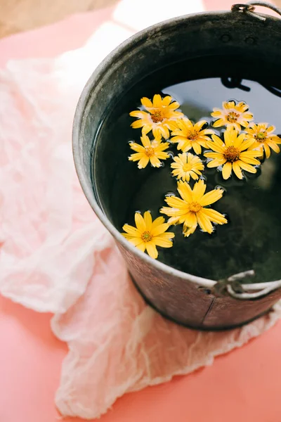 yellow flowers in a bucket of water