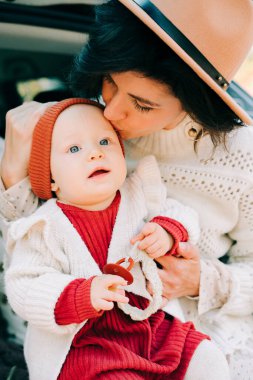 Güzel bir anne ve kız çam ormanında rahat bir arabanın bagajında oturuyorlar.