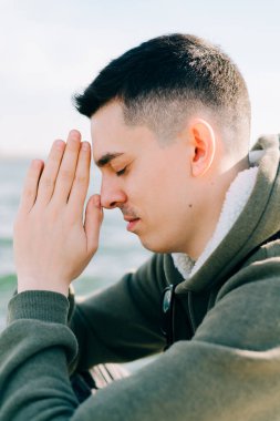 Genç bir adam gölün yanındaki iskelede oturmuş meditasyon yapıyor.