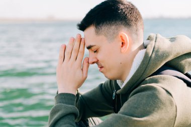 Genç bir adam gölün yanındaki iskelede oturmuş meditasyon yapıyor.