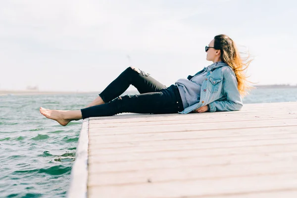 Genç Güzel Şık Bir Kız Gölün Yanındaki Iskelede Oturuyor — Stok fotoğraf