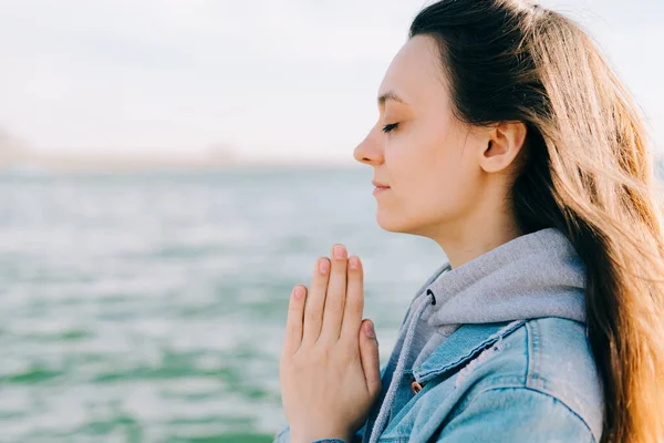 Genç ve güzel bir kız gölün yanındaki iskelede oturuyor ve meditasyon yapıyor.