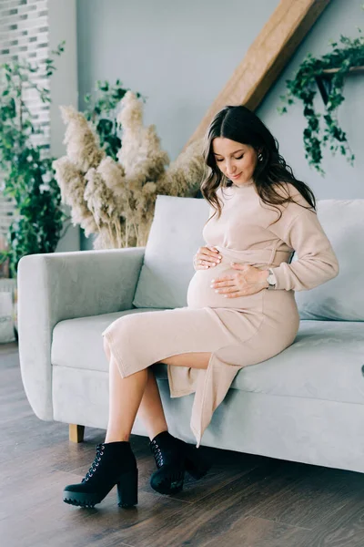 Una Joven Mujer Embarazada Hermosa Vestido Beige Sentado Sofá Gris — Foto de Stock