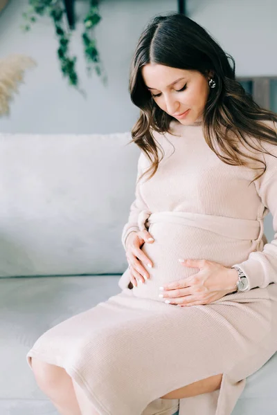 Retrato Una Joven Mujer Embarazada Hermosa Vestido Beige Sentado Sofá — Foto de Stock