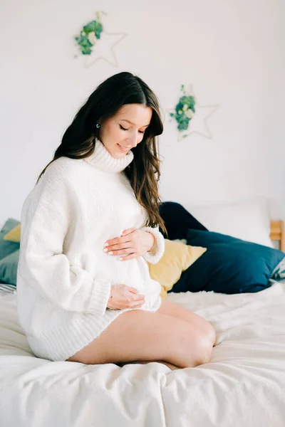 Joven Mujer Embarazada Feliz Suéter Blanco Caliente Sentado Cama Sosteniendo — Foto de Stock