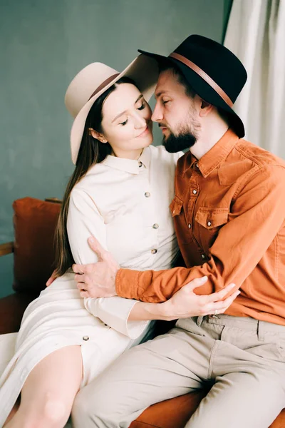Stilvolles Verliebtes Paar Mit Hüten Sitzt Auf Einem Braunen Sofa — Stockfoto