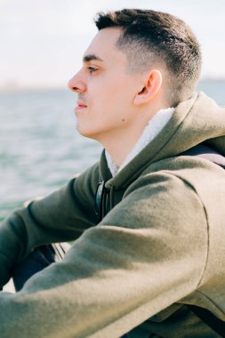 Genç bir adam gölün yanındaki iskelede oturmuş meditasyon yapıyor.