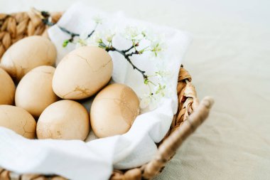 Masanın üzerinde doğal bir hasır sepet var. Beyaz bir peçetede çatlaklar olan birkaç Paskalya yumurtası. Modaya uygun bir pastel tonda boyanmış. Paskalya konsepti.