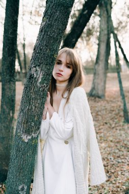 Açık beyaz elbiseli, siyah ayakkabılı, genç ve çekici bir kızın portresi.