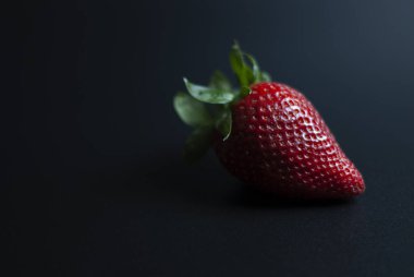 Siyah arkaplanda bir kırmızı çilek