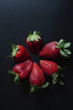Siyah arka planda 6 kırmızı çilek