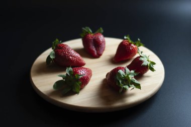 Ahşap döner tepside taze çilek ve siyah arka plan.