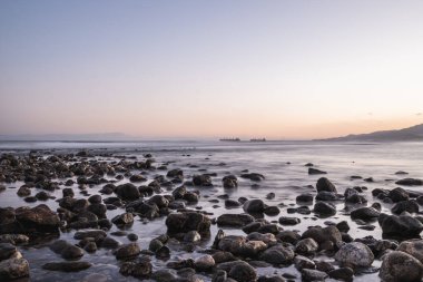 Sahilde gün batımı kayalıklarla