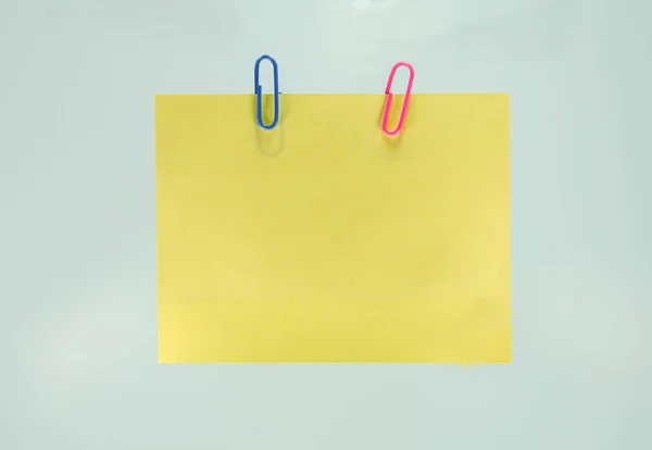 Yellow sheet of paper for notes and paperclip — Stock Photo, Image