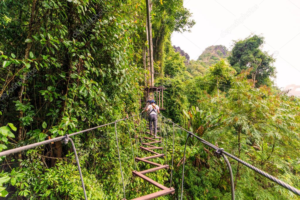 man going on zipline adventure through the forest in Lao