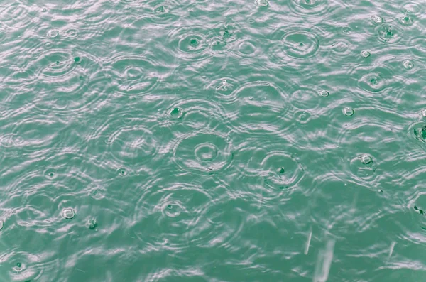 Gocce di pioggia in acqua blu sul lago — Foto Stock