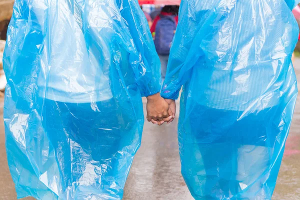 Couples in raincoat holding hands walking on rain