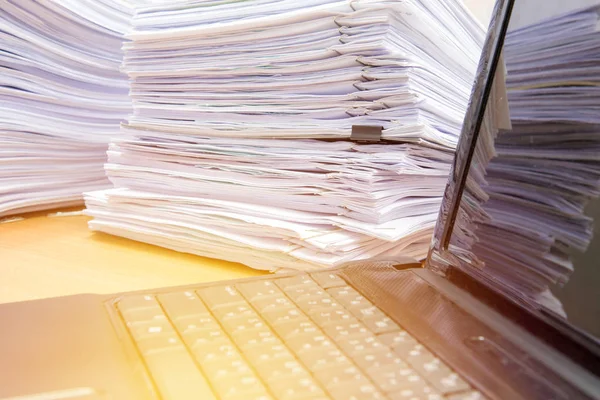Notebook de computador e documentos na mesa empilhar alto esperando para — Fotografia de Stock