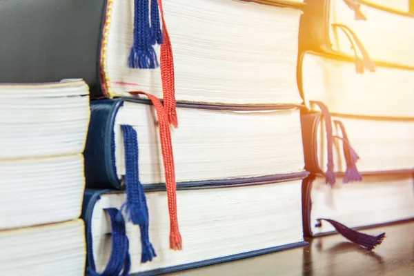 Muitos livros empilham em mesa de madeira na biblioteca — Fotografia de Stock