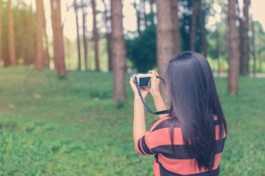 Genç kadın turist ile fotoğraf makinesi ve çam ormanı içinde alarak fotoğraf