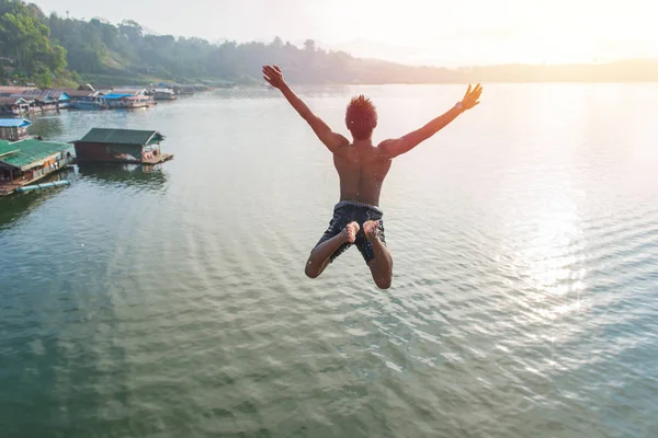 Человек, прыгающий в озеро ретро на длиннейшем деревянном мосту в Сангкхле — стоковое фото