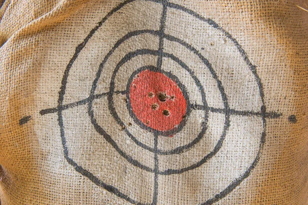 Target gun with bullet holes over sack background — Stock Photo, Image