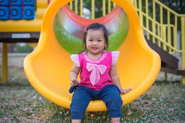 Маленькая девочка играет на горке на детской площадке — стоковое фото