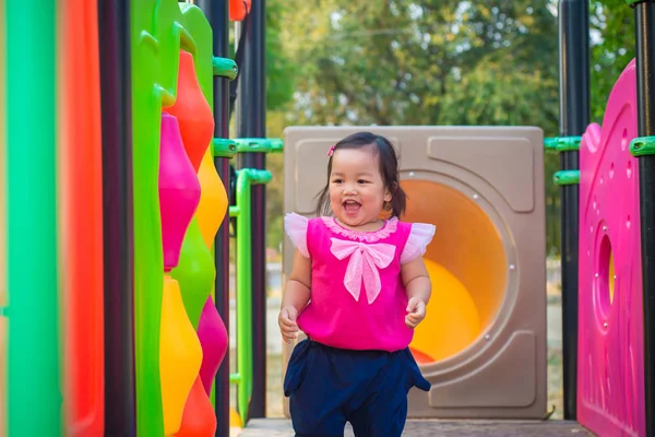 Niña jugando en un tobogán en el parque infantil —  Fotos de Stock