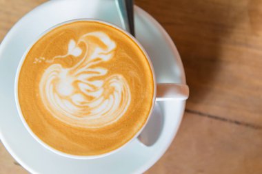 Latte art kahve ya da ahşap masa zemininde kapuçino.