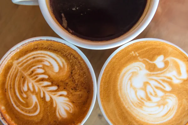 Latte umění káva nebo cappuccino na dřevěném stole pozadí — Stock fotografie