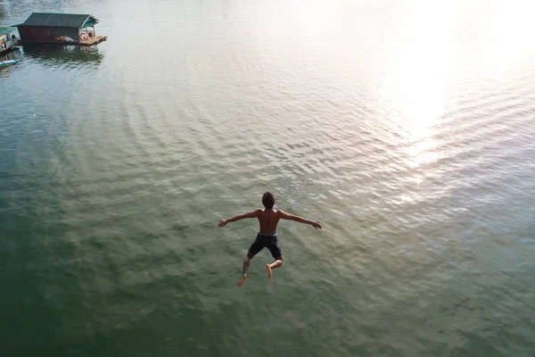 Hombre saltando en el lago retro en el puente de madera más largo de sangkhla — Foto de Stock