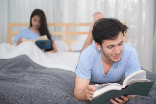Молодая любящая пара читает книгу о спальне дома — стоковое фото