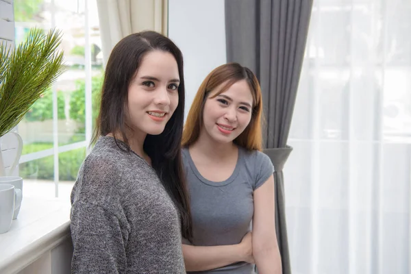 Portrait of two young woman standing in living room at home