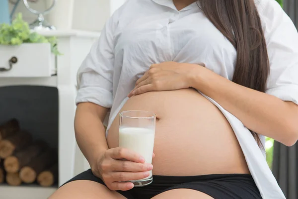 Mujer embarazada sosteniendo un vaso de leche fresca para la atención sanitaria —  Fotos de Stock