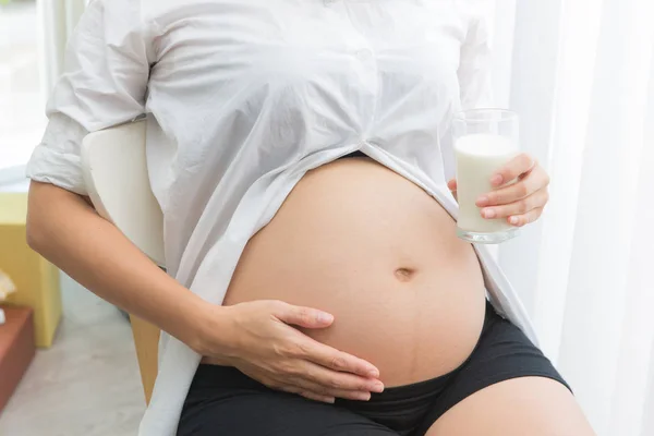 Mujer embarazada sosteniendo un vaso de leche fresca para la atención sanitaria —  Fotos de Stock