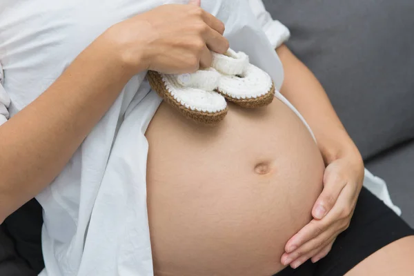 Scarpe piccole per il bambino nella pancia della donna incinta — Foto Stock