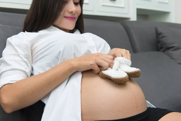 Zapatos pequeños para bebé en el vientre de la mujer embarazada — Foto de Stock