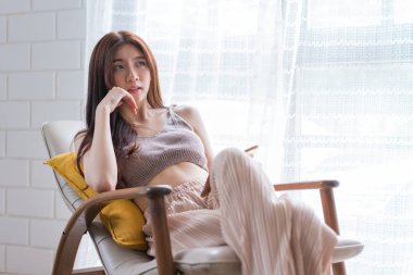 Asyalı bir kadın oturma odasında akıllı bir şekilde kanepede oturuyor, eğitim teknolojisi ve internet konseptini kullanıyor..