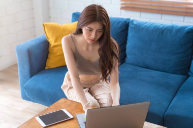 Oturma odasında akıllı davranarak kanepede rahatlayan genç bir kadın.,