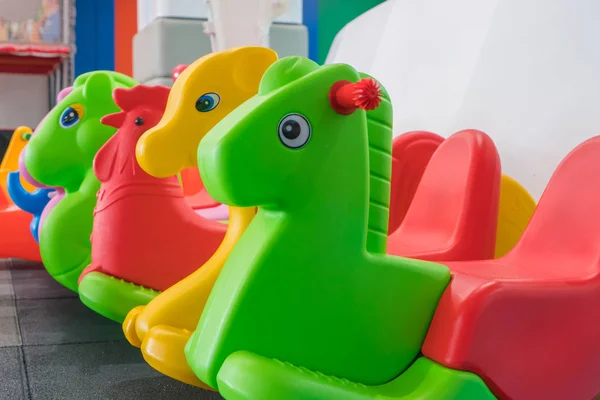 Kids colorful horse rocking chair on indoor playground for the k — Stock Photo, Image