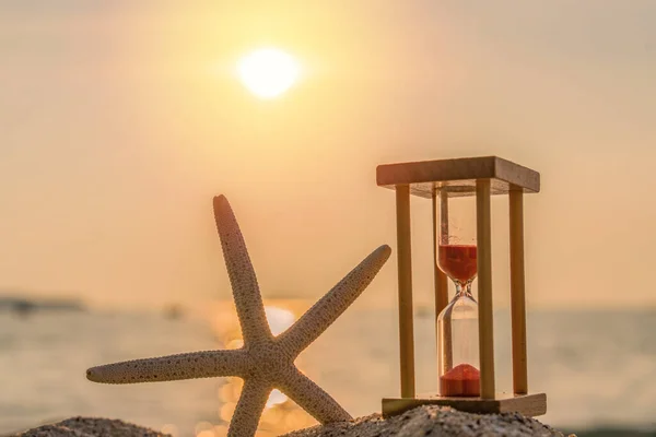 Időkoncepció Homokóra és tengeri csillag a homokos tengerparton nyáron szellemes — Stock Fotó