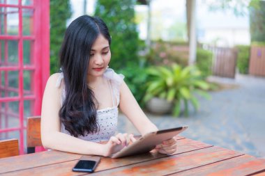 Bahçede oturan genç kadın dijital tablet, eğitim teknolojisi ve internet kavramı kullanıyor.