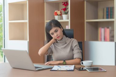 Genç iş kadını ya da sekreteri dizüstü bilgisayarla çalışıyor ve ofiste çok çalıştıktan sonra boyun ve omuz ağrısı çekiyor. Ofis sendromu semptomu yüzünden çok acı ve hastalık hissediyor..