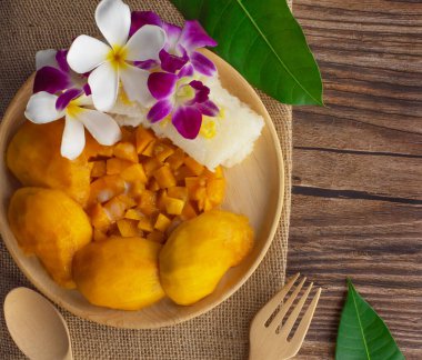 Ahşap bir arka planda ahşap tabakta servis edilen mangolu pilav. Otantik Taylandlı ünlü tatlı..