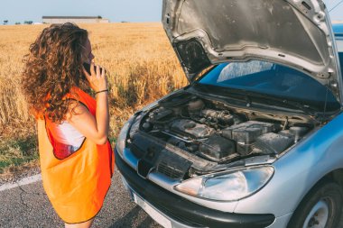Bozuk bir arabanın önünde bir kız arıyor.