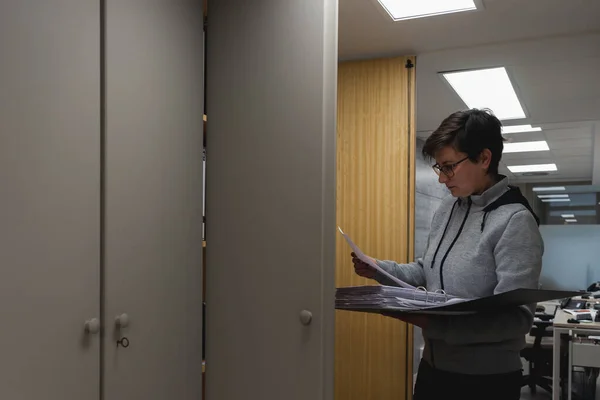 Young woman looking for work papers in filing cabinet